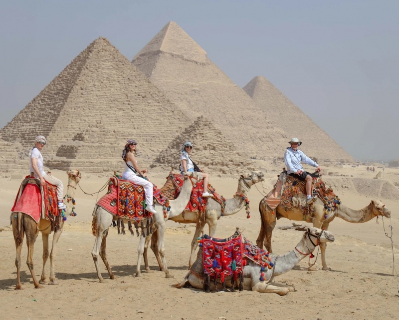 Riders on camels in front of the Giza pyramids