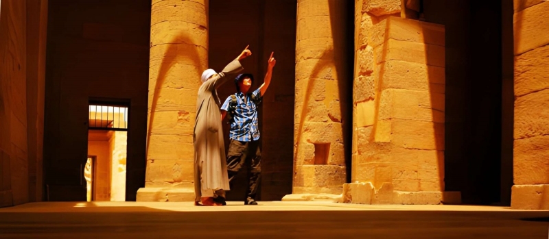 Guide inside an Egyptian temple A guide points out details to a visitor between the columns of an ancient Egyptian temple