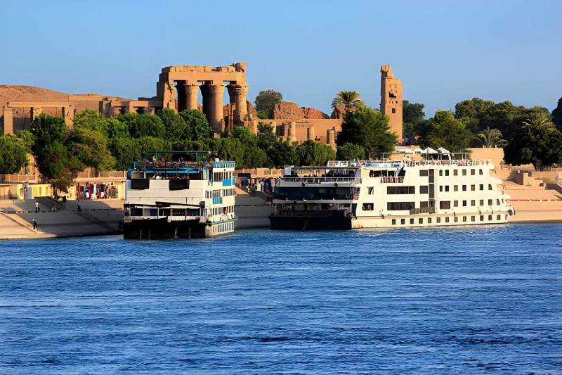 Nile cruise ships moored beside a temple on the riverbank