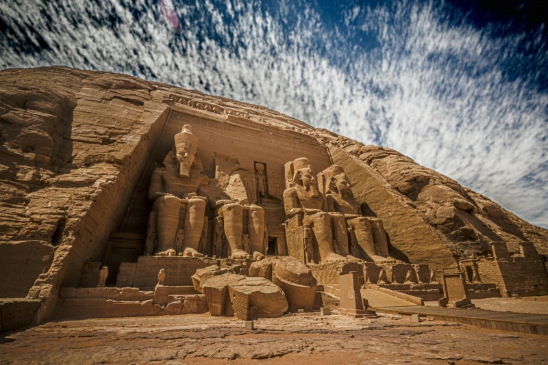 The colossal statues at the entrance of the Abu Simbel Great Temple under a streaked sky